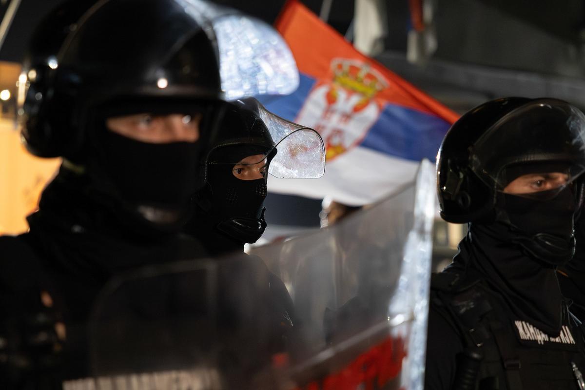 Žandarmi iza štitova sa srpskom zastavom u pozadini